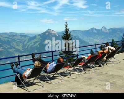 Un gruppo di turisti godono di una vista panoramica delle Alpi svizzere mentre sdraiati su una piattaforma di osservazione in Beckenried, Svizzera. Foto Stock