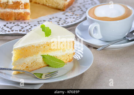 Voglia di torta con yogurt e crema di formaggio, servita con un cappuccino Foto Stock