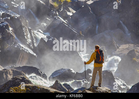 Escursionista escursionismo con zaino guardando a cascata Foto Stock