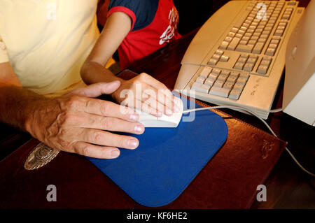 Nonno e nipoti al computer, le mani sul mouse PC © Credito luigi innamorati/sintesi/alamy stock photo.Caption locale *** Foto Stock