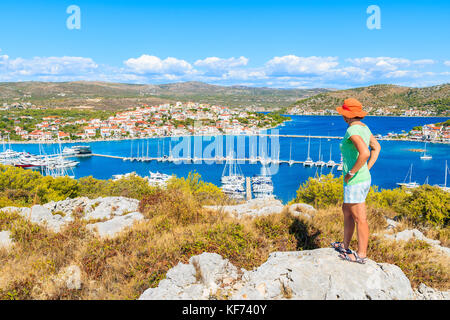 Giovane donna per turisti in cerca a Rogoznica porto e le barche a vela dal punto di vista elevato, Dalmazia, Croazia Foto Stock