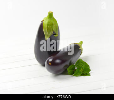 Due melanzane fresche e salvia su bianco sullo sfondo di legno Foto Stock