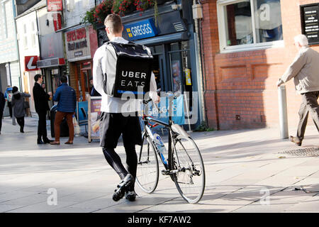 Giovane uomo che cammina in bicicletta e UBER MANGIA) cibo consegna zaino indietro vista Cardiff City Centre Wales UK KATHY DEWITT Foto Stock