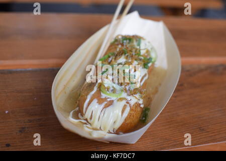 Una porzione di takoyaki giapponese, una tipica merenda a base di frumento a base di farina di pastella con pezzi di polpo all'interno Foto Stock