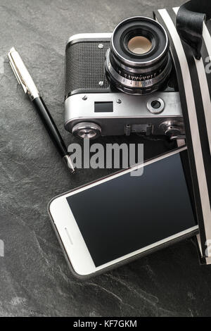 Telefono, fotocamera, penna in un sacco nero con strisce bianche di close-up verticale Foto Stock