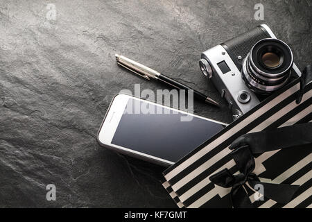 Telefono, fotocamera, penna in un sacco nero con strisce bianche spazio libero in orizzontale Foto Stock