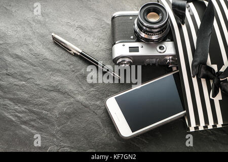 Telefono, fotocamera, penna in un pacchetto nero con strisce bianche con l'orizzontale a destra Foto Stock
