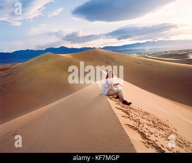 USA, California, giovane donna seduta su duna di sabbia, stovepipe Wells, Death Valley National Park Foto Stock