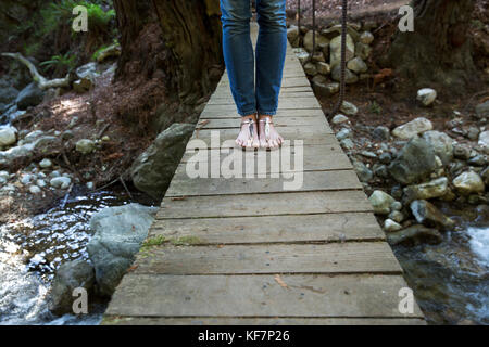 Stati Uniti, California, Big Sur, esalen, una donna in piedi su un piccolo ponte al di sopra di hot springs creek a Esalen Institute Foto Stock