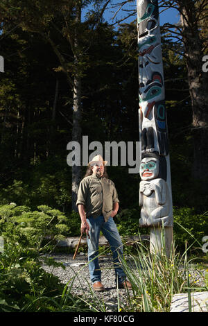 Stati Uniti d'America, Alaska, Sitka, tommy Giuseppe un tinglit totem pole carver si erge di fronte a uno dei suoi intagli, Halibut Cove, sitka sound Foto Stock