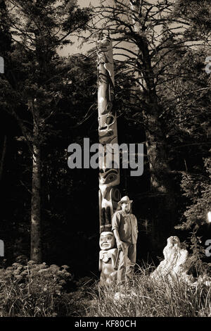 Stati Uniti d'America, Alaska, Sitka, tommy Giuseppe un tinglit totem pole carver si erge di fronte a uno dei suoi intagli, Halibut Cove, sitka sound Foto Stock