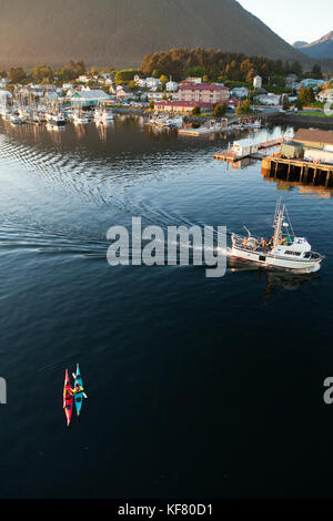 Stati Uniti d'America, Alaska, Sitka, kayakers prendere un periodo di riposo in sitka Harbour mentre una barca da pesca passa da Foto Stock