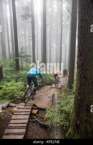 Canada Vancouver, British Columbia, Andrew baker e jordi morros mountain bike attraverso la foresta pluviale nella nebbia in North Vancouver Foto Stock