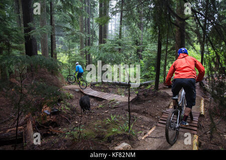Canada Vancouver, British Columbia, Andrew baker e jordi morros mountain bike attraverso la foresta pluviale nella nebbia in North Vancouver Foto Stock