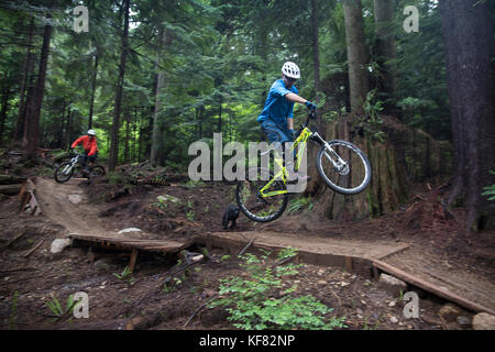 Canada Vancouver, British Columbia, mountain biker andrew baker riceve aria su un sentiero nella foresta pluviale, North Vancouver Foto Stock