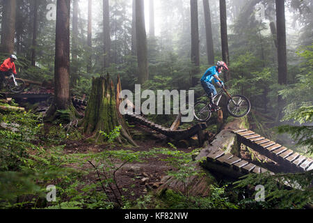 Canada Vancouver, British Columbia, mountain biker andrew baker riceve aria su un sentiero nella foresta pluviale, North Vancouver Foto Stock