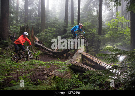 Canada Vancouver, British Columbia, mountain biker andrew baker riceve aria su un sentiero nella foresta pluviale, North Vancouver Foto Stock