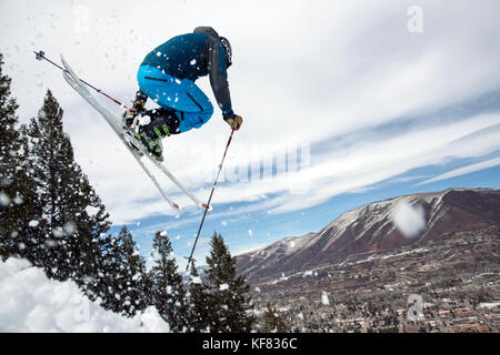 Stati Uniti d'America, colorado, Aspen, sciatore prendere l'aria su un sentiero denominato cavatappi con la città di Aspen in distanza, aspen ski resort, monte Ajax Foto Stock