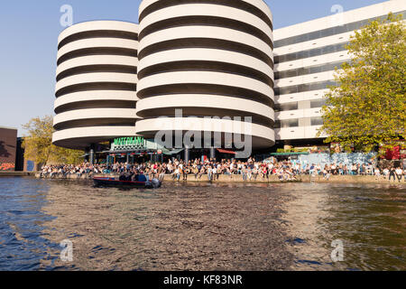 Persone che si godono il sole autunnale sul litorale dei canali di Amsterdam Foto Stock