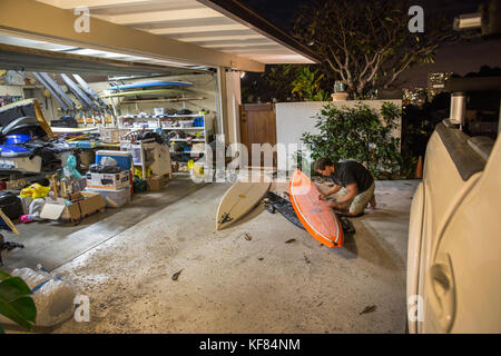 Stati Uniti d'America, Hawaii Maui, ganasce, big wave surfer mike pietsch preparandosi sue assi nella sua casa di Oahu prima di uscire per navigare peahi sulla northshore Foto Stock