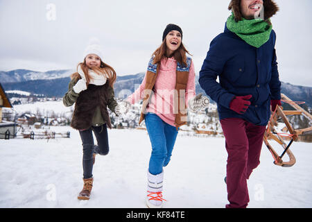 La famiglia che corre attraverso le colline innevate Foto Stock