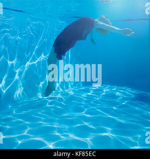 L'Europa, Spagna, Balearen, Mallorca, una piscina a Canyamel - una donna underwater flottante con abito rosso Foto Stock