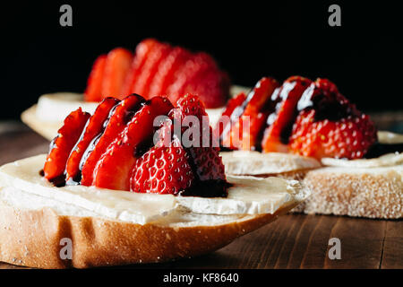 Crostini con formaggio brie, fragole fresche rustico superficie in legno Foto Stock