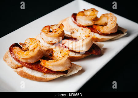 Gustoso il chorizo e gamberi alla griglia su crostini tostati Pane italiano Foto Stock