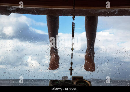 Indonesia, Flores, piedi e una croce pendono dal tetto di una barca che è rotta in labuan bajo Foto Stock