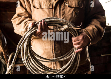 Stati Uniti d'America, oregon, enterprise, cowboy todd nash mantiene la sua corda a snyder ranch dopo una lunga giornata di bovini in movimento sotto la pioggia, nordest oregon Foto Stock