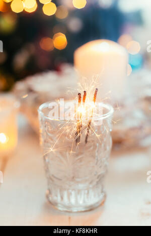 Botti all'interno di un bicchiere sulla tavola del Natale con albero di natale in background Foto Stock