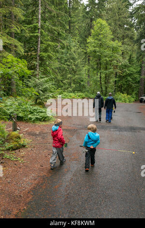 Stati Uniti d'America, oregon, santiam river, marrone cannon, due giovani ragazzi camminando dietro di loro papà nel willamete foresta nazionale sul loro modo al fiume santiam Foto Stock