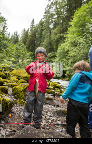 Stati Uniti d'America, oregon, santiam river, marrone cannone, un giovane ragazzo che mostra fuori il pesce ha catturato nel fiume santiam Foto Stock