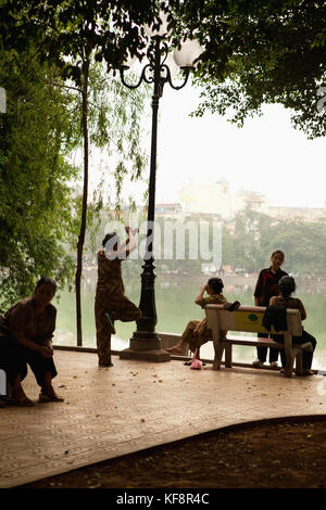 Il Vietnam, Hanoi, donne socializzare e praticare il tai chi al mattino presto, il lago Hoan Kiem Foto Stock