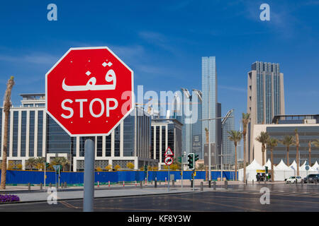 Dubai,United Arab Emirates di - 7 febbraio 2012: bilingue segno di stop in Dubai con entrambi in arabo e in scrittura Latina.tipica architettura moderna su una SAN Foto Stock