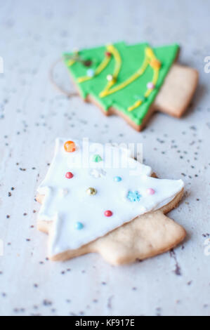 Due gingerbread cookies a forma di bianco e verde albero di natale sullo sfondo di un tavolo in legno e sparse semi di Chia. Foto Stock