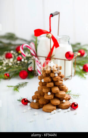 Festa di Natale composizione con una struttura ad albero dei cookie e delle bottiglie con latte sullo sfondo Foto Stock