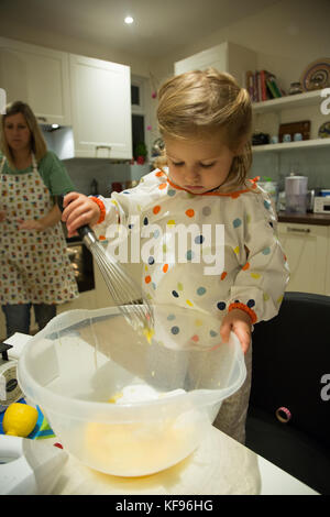 Giovani toddler miscelazione degli ingredienti in preparazione per la cottura di una torta Foto Stock