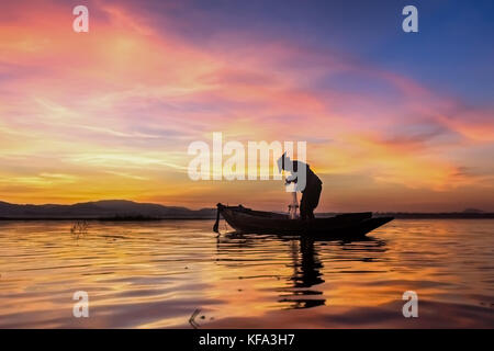 Fisherman è l'impostazione rete da pesca sulla barca con sunrise Foto Stock