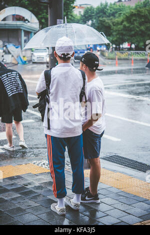 Popolo coreano in attesa in un crosswalk sotto la pioggia Foto Stock