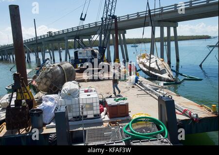 Della guardia costiera statunitense ufficiali ed equipaggi di risposta rimuovere barche danneggiate dal tasto di avvio di Harbour City marina durante gli interventi di soccorso dopo il passaggio dell uragano irma ottobre 16, 2017 in maratona, Florida. (Foto di j.t. blatty via planetpix) Foto Stock