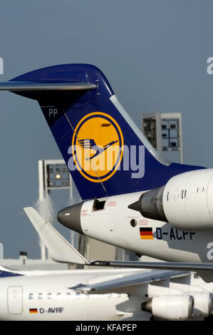 CRJ coda con logo, alette e motori passando il terminale 1 con un Lufthansa BAE 146 RJ-85 dietro Foto Stock