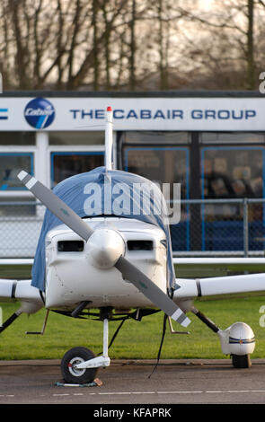 Un Cabair Grumman American AA-5B Tiger parcheggiata con la scuola di volo dietro Foto Stock