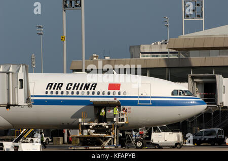 La Air China International CA CCA Airbus A340-313X parcheggiato presso il terminale con veicoli di bagaglio Foto Stock