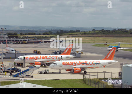 Due easyJet Airbus A319-100s parcheggiato sul piazzale di sosta con veicoli aeroportuali e airstairs Foto Stock