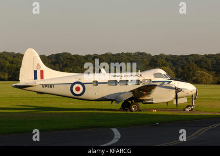 Un Royal AirForce de Havilland DH-104 Devon C-2 parcheggiato sul piazzale con alberi dietro Foto Stock