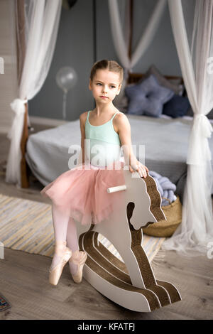 Carino piccola ragazza sogna di diventare una ballerina. Bambino ragazza in un rosa tutu dancing in una stanza. Baby girl sta studiando il balletto. Foto Stock