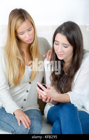 Ragazza con un amico di essere vittima di bullismo mediante messaggio di testo Foto Stock