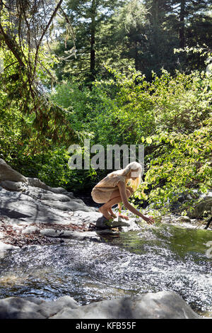 Stati Uniti, California, Big Sur, esalen, una donna mette la sua mano in hot springs creek a Esalen Institute Foto Stock