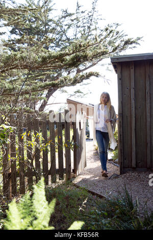 Stati Uniti, California, Big Sur, esalen, donna cammina attraverso un cancello accanto al legno poco yurta presso l istituto di esalen Foto Stock